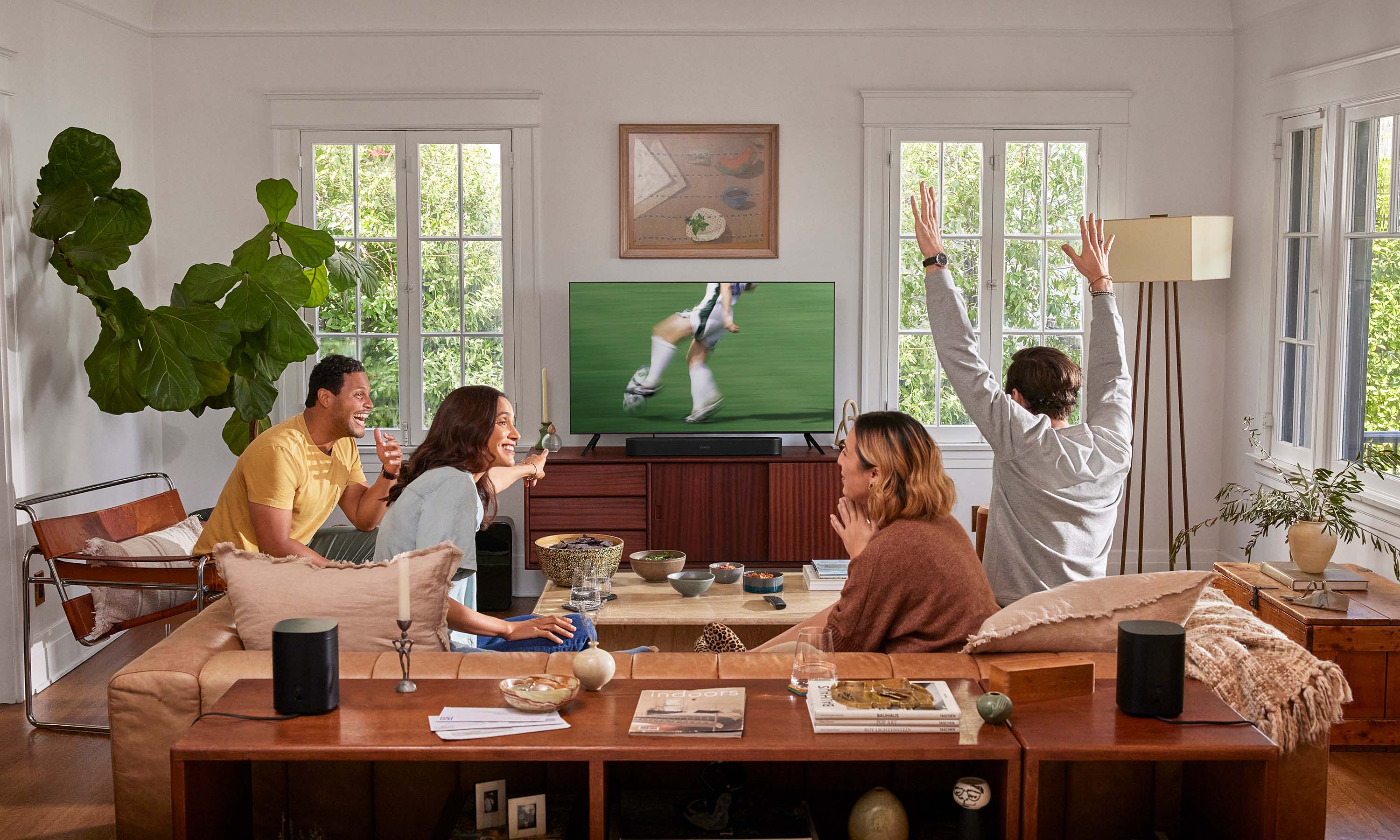 friends gathering around a tv with sonos technology
