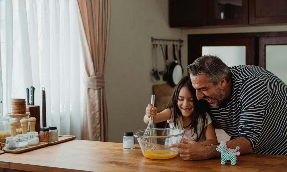 Grandfather and granddaughter cooking together in kitchen