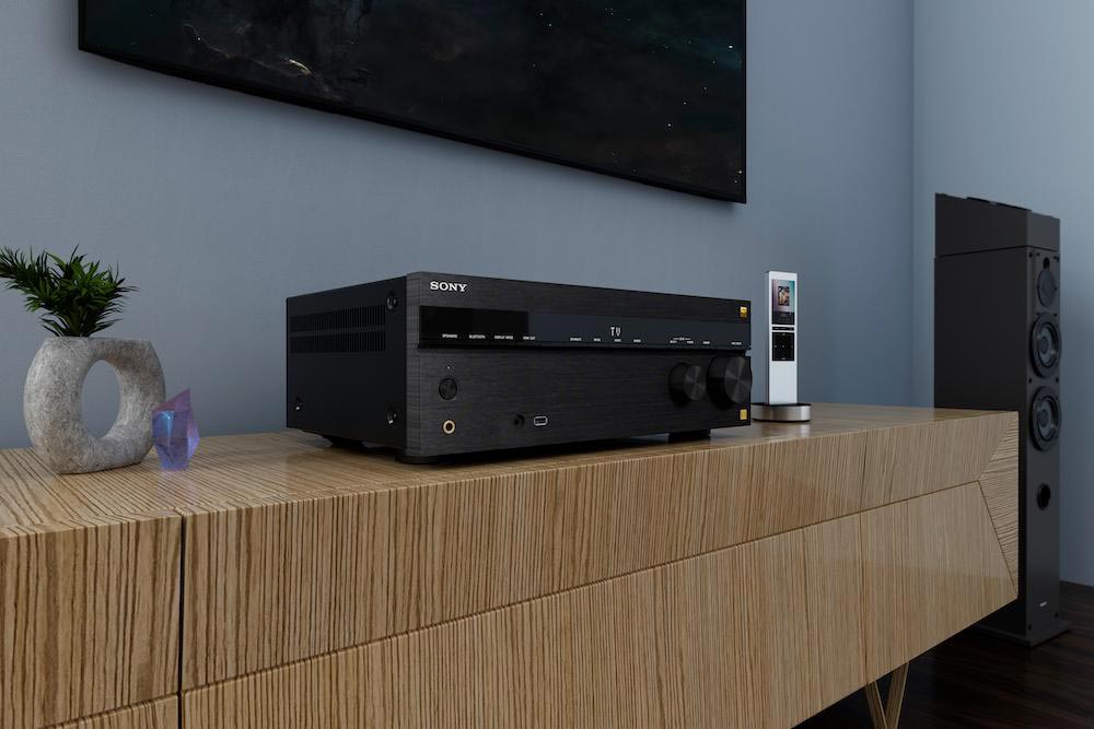A Sony AV receiver placed on a wooden console table, paired with a sleek remote control and decorative items.
