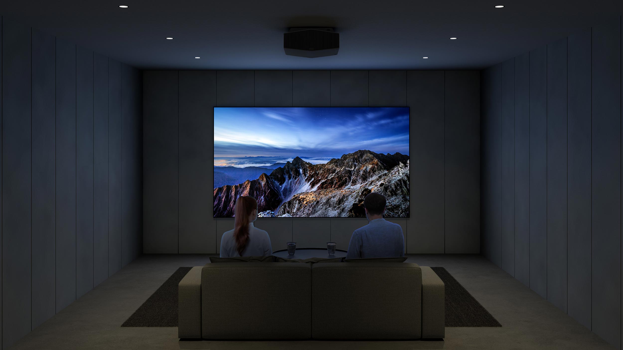 A cozy home theater with a ceiling-mounted projector displaying a vivid mountain landscape.