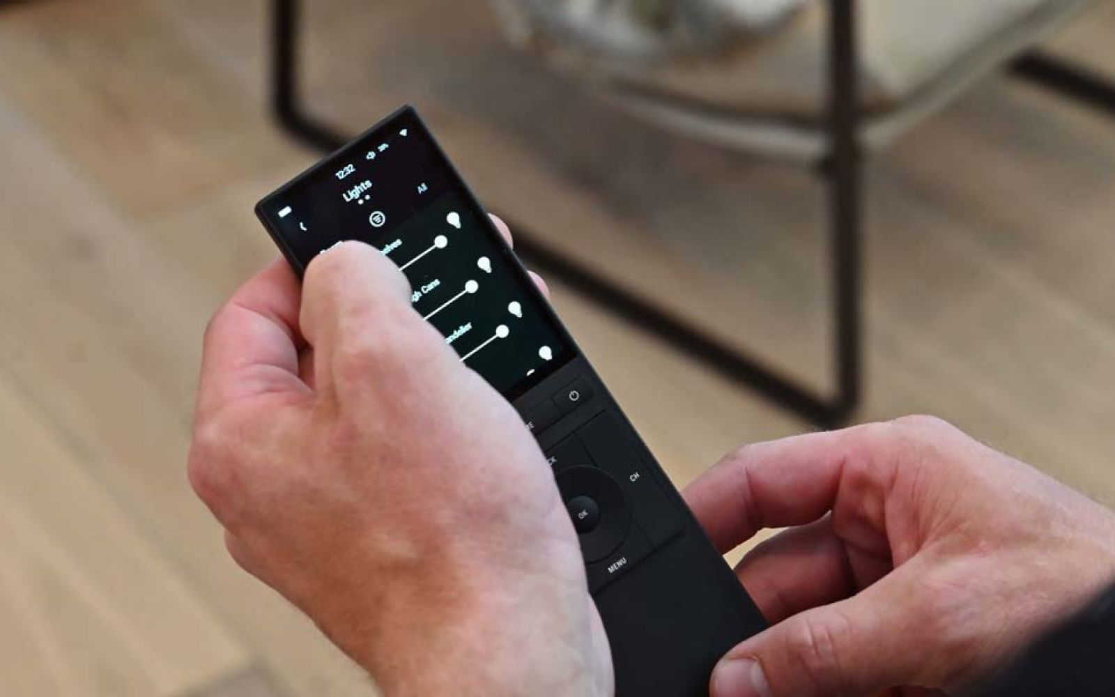 Hand adjusting smart home settings on black touchscreen remote
